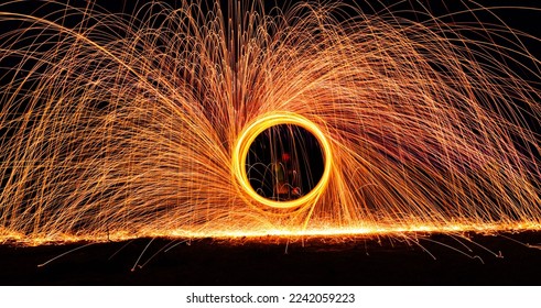 A dramatic glowing long exposure of  spinning light trails with sparks - Powered by Shutterstock