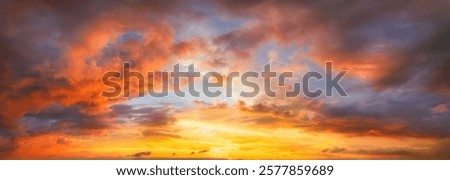 Dramatic glowing sky at sunset with illuminated orange majestic clouds. A vibrant panoramic cloudscape photo.