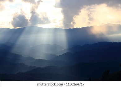 Dramatic god lights passing through clouds and shining on mountain ranges. warm light shower. God hope and dream concept