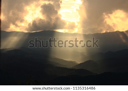 Dramatic god lights passing through clouds and shining on mountain ranges. warm light shower. God hope and dream concept