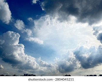 Dramatic God Rays Sunbeam Piercing Through Clouds Over City Skyline Silhouette