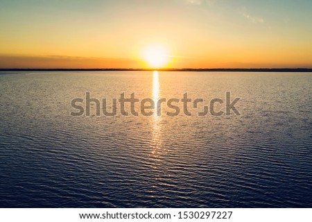 Dramatic golden beach sunset sky and tropical sea background. yellow sun sets behind the lake. Beautiful sunrise on the lake. Protect the environment. sun sets ha horizon