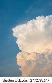 Dramatic golden cumulus clouds in a soft blue sky during sunset. The fluffy cloud formation creates a majestic and peaceful background.