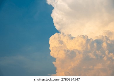 Dramatic golden cumulus clouds in a soft blue sky during sunset. The fluffy cloud formation creates a majestic and peaceful background.
