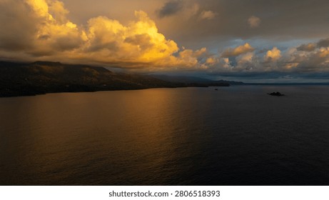 Dramatic golden and dark clouds hanging over a tropical coastline and ocean water during sunset light in costa rica