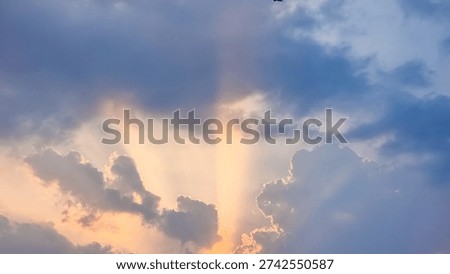 Dramatic golden sunbeams breaking through dark clouds at sunset. Beautiful light rays and sky background for hope and nature concepts.