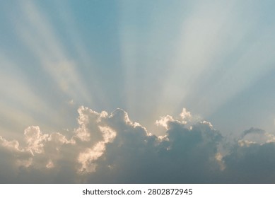 Dramatic golden sunrays bursting through layered clouds across a wide open blue sky