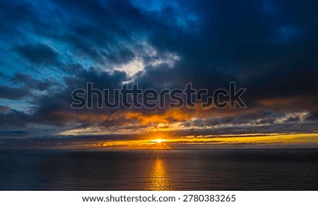 Dramatic Golden Sunset with Sun Rays over Dark Atlantic Ocean under Stormy Sky, Iceland