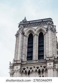 A dramatic Gothic facade rises against an overcast sky, showcasing ornate stone details and timeless European architectural grandeur.