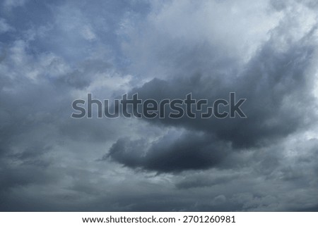 Dramatic gray clouds gathering, ominous stormy sky casting shadows, evokes a sense of impending weather change.