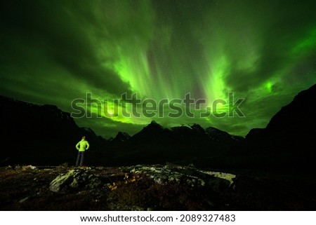 Dramatic green northen light visible via clouds in Lapland, Sweden