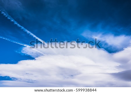 Dramatic HDR blue sky with huge fluffy white clouds and jet traces, tracks