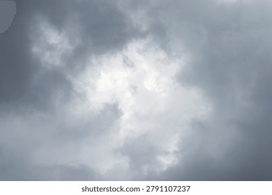 A dramatic and heavy overcast sky filled with dense gray storm clouds surrounding a brighter, central break in the cloud cover