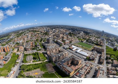Dramatic, highly distorted aerial panorama showing a vibrant European town with residential, commercial, and green zones under a vivid blue sky.