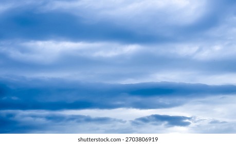 Dramatic horizontal stratocumulus clouds in deep blue and cold gray tones across the sky, suggesting heavy weather, storm, or a moody backdrop.