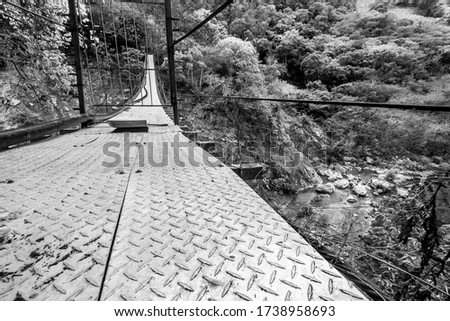 dramatic image of a cable walk bridge on rio Ocoa, dominican republic, in the Ocoa province with rocks and river 50 feet below.