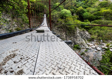 dramatic image of a cable walk bridge on rio Ocoa, dominican republic, in the Ocoa province with rocks and river 50 feet below.