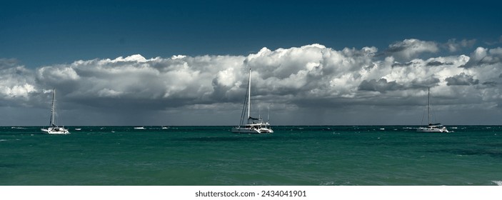Dramatic image of the Caribbean coast in Las Terrenas with sailboats anchored in the stormy bay with cloudy skies.