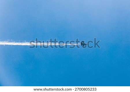 Dramatic image of a fighter jet deploying brilliant flares while climbing rapidly into a vast blue sky. High-impact action and vivid contrast.