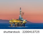 Dramatic image of an offshore oil platform off the coast of California against a pink winter sky as the sun sets and the rig