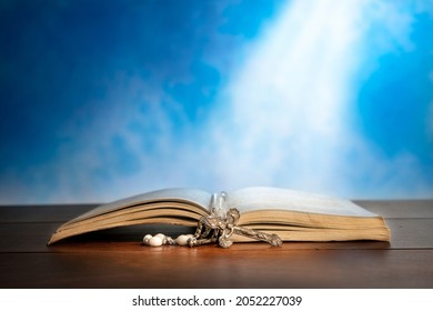 Dramatic image showing a bright light beam shining on an old bible with a rosary laying in front of it.

 - Powered by Shutterstock