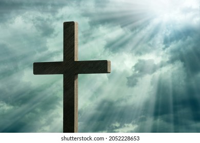 Dramatic image showing a religious church cross framed against a moody sky that is beginning to open and pierce light through behind the cross, showing the Lord's presence. 

 - Shutterstock ID 2052228653