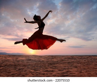 Dramatic image of a woman jumping above the ocean at sunset, silhouette