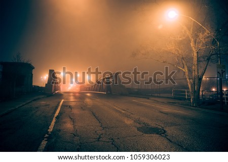 Dramatic industrial vintage river road bridge street scene at night with illuminating fog in Chicago