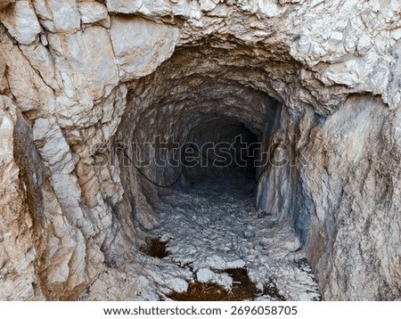 dramatic interior of rocky cave featuring puddle reflection and accentuated textures with striking
