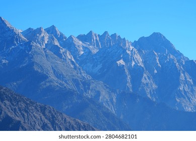 Dramatic jagged mountain peaks in Gilgit Baltistan Pakistan under clear sky creating powerful alpine scenery.
