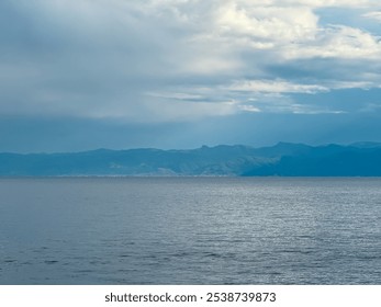 Dramatic lakeside scene at Lake Ohrid, North Macedonia. Stormy sky casting shadows over hills and mountains. Brewing storm with dark clouds accumulating. Power and beauty of nature. Boat tour - Powered by Shutterstock