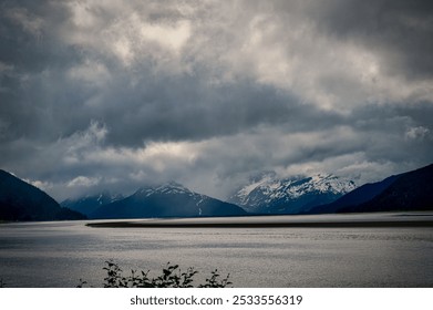 A dramatic landscape of a cloudy sky over snow-capped mountains and a calm lake. - Powered by Shutterstock - Get 15% off with code: PIKWIZARD15