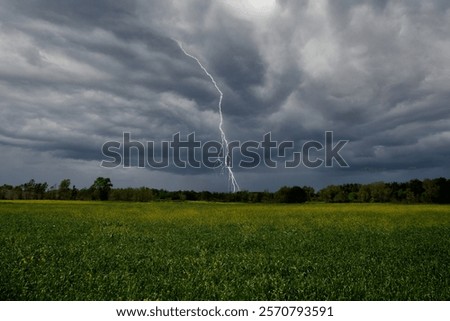 A dramatic landscape with cultivated fields and a stormy sky, featuring lightning
