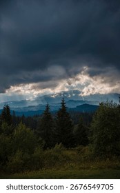 Dramatic landscape with dark clouds over a forested mountain range.