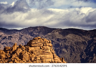 Dramatic landscape featuring rugged middle atlas mountains in morocco with a large orange rock formation dominating the foreground