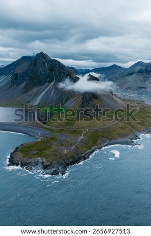 Dramatic landscape of Iceland captures a rugged coastline accented by towering mountains and rolling clouds. Hvalnes Nature Reserve