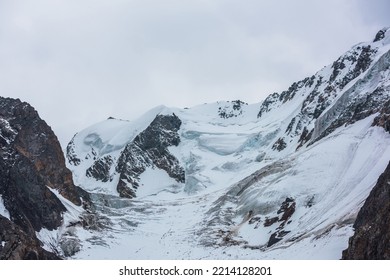 Dramatic landscape with large snow mountain top with ice cornice and glacier under gray cloudy sky. Big glacier with icefall on high altitude. Gloomy scenery in snowy mountains in overcast close-up. - Powered by Shutterstock