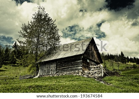 Dramatic landscape with an old barn on a meadow and moody sky