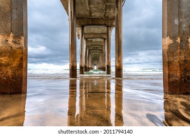 A dramatic landscape on the ocean in cloudy weather, a beautiful pier in in La Jolla California. Striped sand on the beach