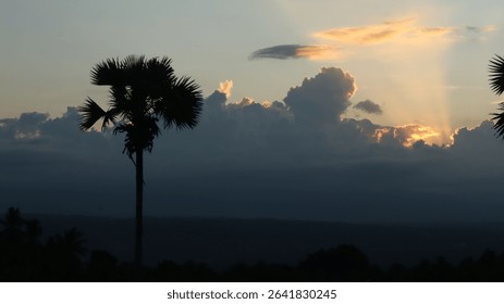Dramatic landscape with sun rays piercing through thick dark clouds over a tropical forest and distant mountains. Ideal for themes of hope, peace, nature, and spirituality.