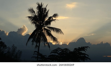Dramatic landscape with sun rays piercing through thick dark clouds over a tropical forest and distant mountains. Ideal for themes of hope, peace, nature, and spirituality.