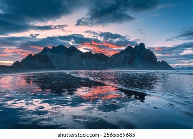 Dramatic landscape of sunset sky over volcanic Vestrahorn mountain reflecting on black sand beach in summer at Stokksnes peninsula, Iceland