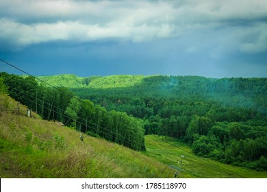 Dramatic Landscape With Thunder Sky And Green Forest. Empty Chairlift In Ski Resort In Summer With Green Grass And No Snow. Ski Resort In Summer.