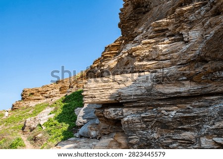 Dramatic layered rock formations on Dongshan Island, Zhangzhou, China. Stratified coastal cliffs showing erosion patterns and geomorphological features with clear blue sky.