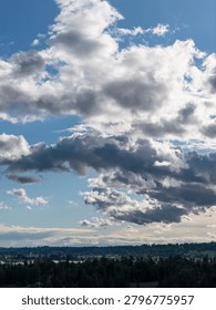 Dramatic layers of clouds and blue sky over the Fraser Valley, BC, Canada, creating moody landscape light.