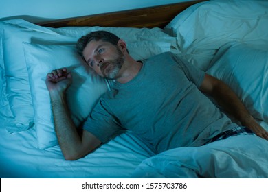 Dramatic Lifestyle Portrait Of Young Attractive Sad And Depressed Man Lying On Bed Awake Thinking At Night Feeling Stressed Suffering Depression Problem In Sadness And Melancholy Concept