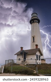 Dramatic lighthouse scene with lightning in coastal California. White lighthouse with red roof and lightning bolts in stormy sky. Awe inspiring nature power on display.