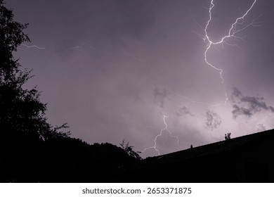 Dramatic Lightning Bolt Illuminating a Dark Sky Over a Rooftop