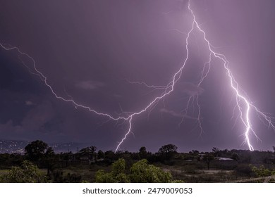 A dramatic lightning storm over a rural landscape with purple skies and distant city lights. Haiti