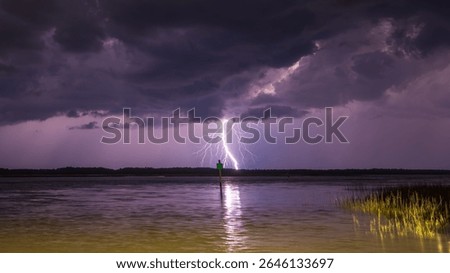 Dramatic lightning strikes over calm waters during a stormy evening in a serene landscape